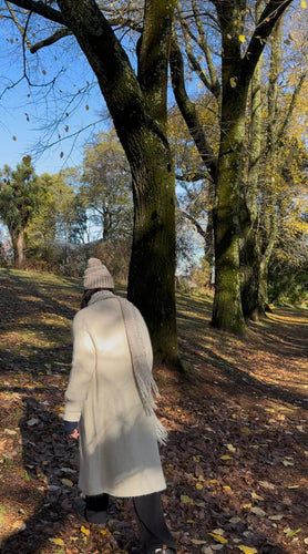A woman walking amongst some autumn trees, wearing alpaca knitwear