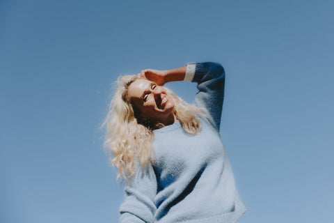 A woman in a blue suri alpaca sweater standing against a blue sky